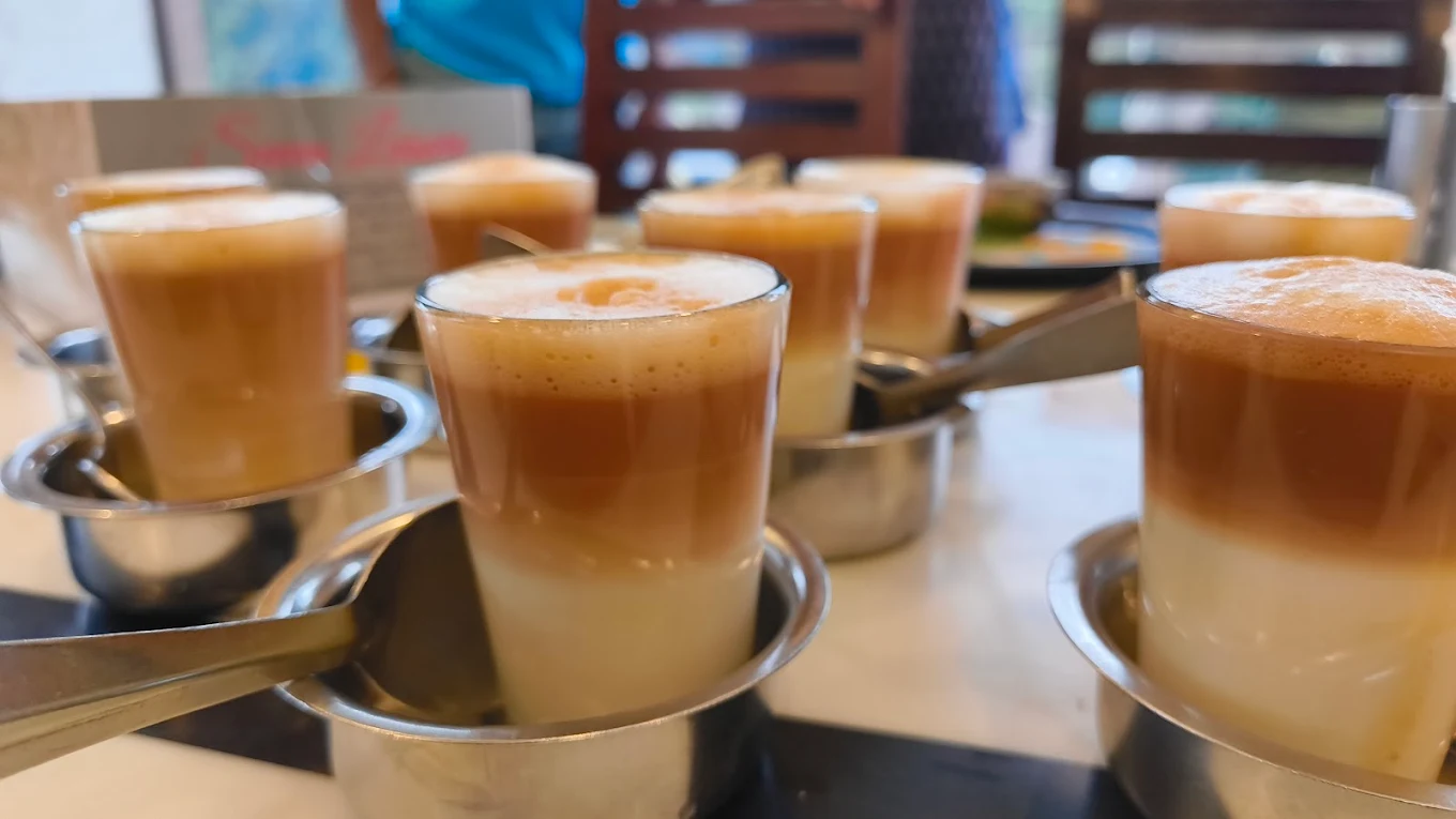 Frothy filter coffee served in glasses with steel tumblers