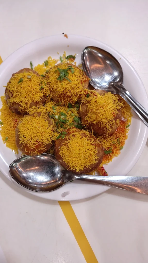 A plate of sev puri topped with fine yellow sev and coriander